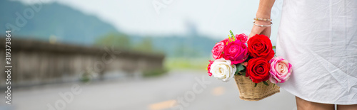 A beautiful woman wearing a white dress shirt standing  her carrying a basket of flowers-panoramic banner for web header