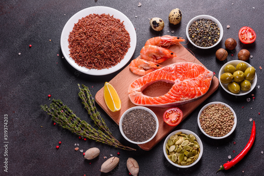 Fototapeta premium Raw trout red fish steak served with herbs and lemon and olive oil on a dark background
