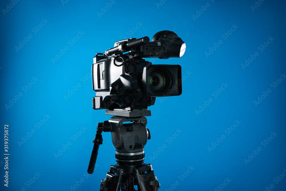 Modern professional video camera on blue background