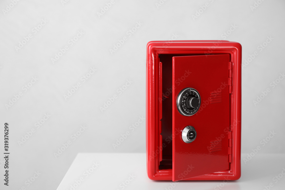 Red steel safe on white table against light background. Space for text Red steel safe on white table against light background. Space for text