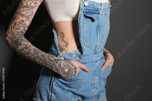 Woman with tattoos on body against black background, closeup