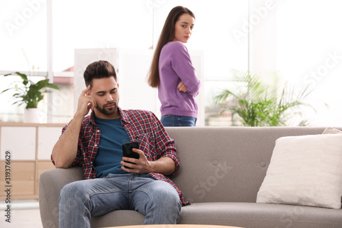Young man preferring smartphone over his girlfriend at home photo