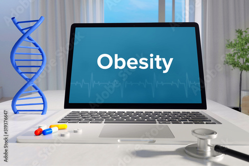 Obesity– Medicine/health. Computer in the office with term on the screen. Science/healthcare