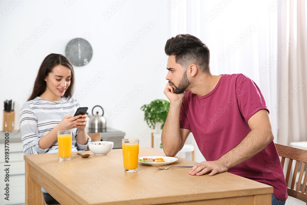 Young woman preferring smartphone over her boyfriend at home Young woman preferring smartphone over her boyfriend at home