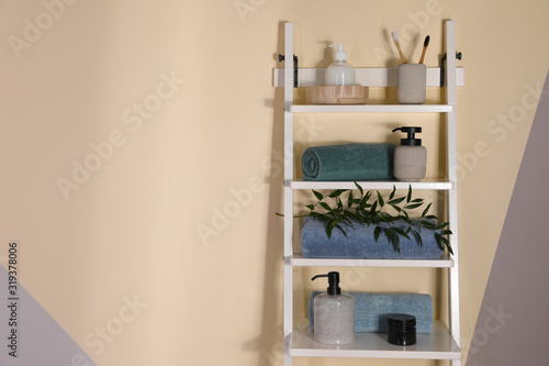 Shelving unit with toiletries near light wall indoors, space for text. Bathroom interior element © New Africa