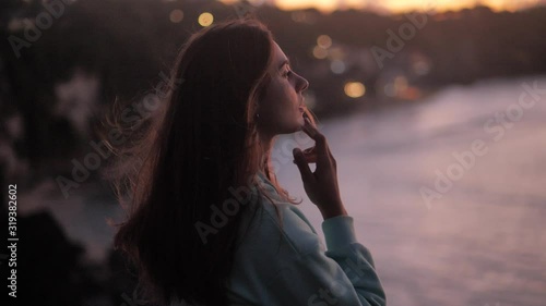Beautiful woman touches her lips and looks to the sky. looking up at purple sky close-up. Silhouette of young woman dreaming looking upwards sunset outdoors. 4