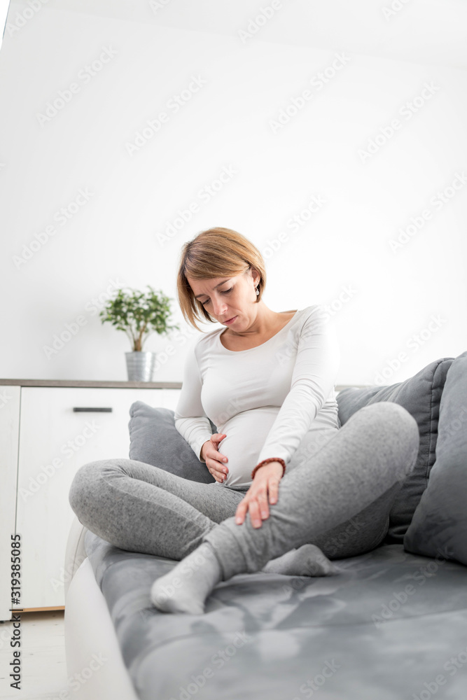 Pregnant tired exhausted woman with stomach, leg and pain issues at home on a couch, being sick. Pregnant tired exhausted woman with stomach, leg and pain issues at home on a couch, being sick.