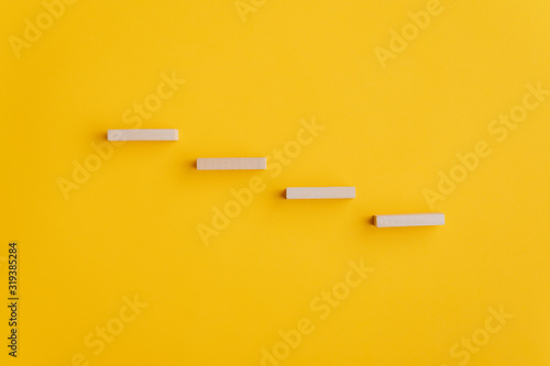 Four blank wooden pegs placed in a stairway like structure