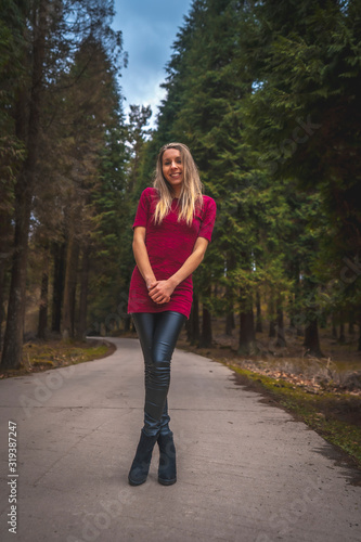 Blonde in a red dress posing in a giant pine forest. Lifestyle session