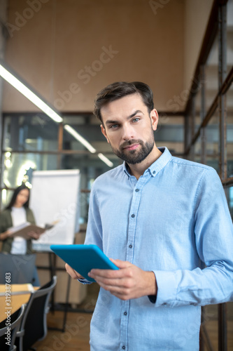 Handsome bearded man with a tablet in his hands looking serious