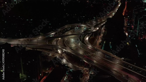 Rising drone shot reveals spectacular elevated highway and convergence of roads, bridges, viaducts in city at night, transportation and infrastructure development in urban area. photo