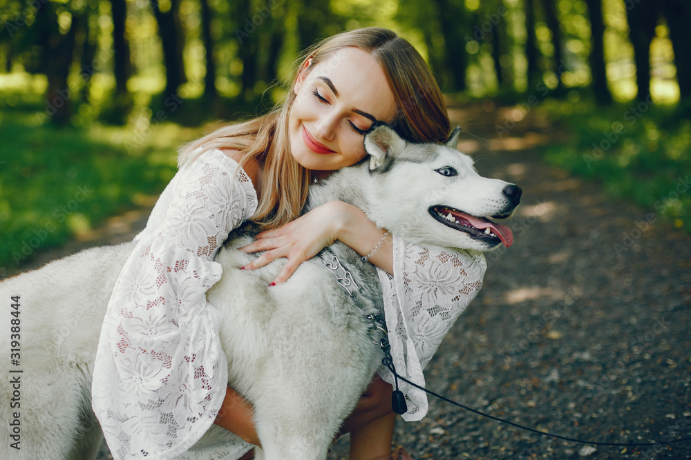 Beautiful and gentle girl with light hair dressed in white dress is playing along with her sweet doggy in summer green park. Beautiful and gentle girl with light hair dressed in white dress is playing along with her sweet doggy in summer green park.