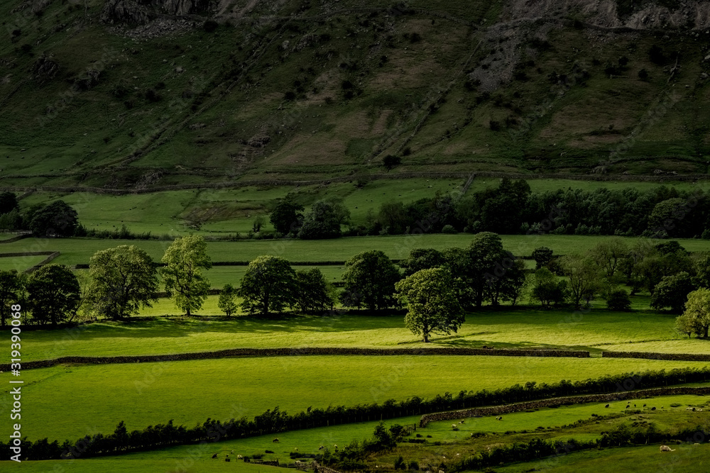 Stormy skies and a bright sun trace light over The Langdale Pikes in the English Lake District