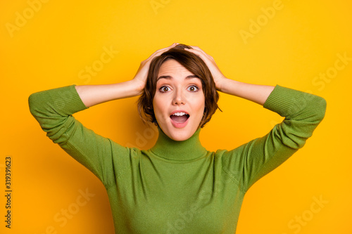 Closeup photo of funny short hairdo lady good mood listen positive news open mouth arms on head wear casual green turtleneck warm sweater isolated yellow color background