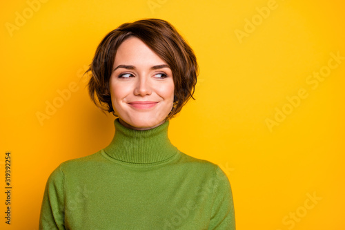 Closeup photo of funny short hairdo lady charming smiling good mood looking side empty space sly eyes wear casual green warm turtleneck isolated yellow color background © deagreez