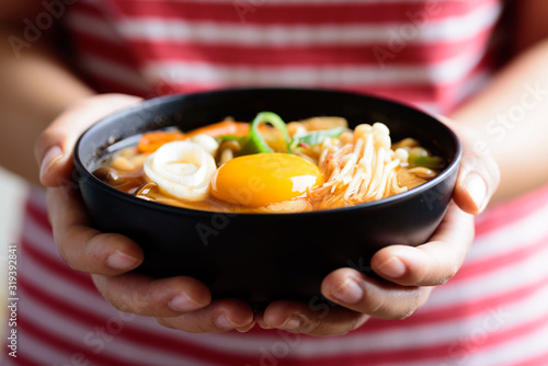 Kimchi soup with mushroom and egg yolk in a bowl holding by hand, Korean food
