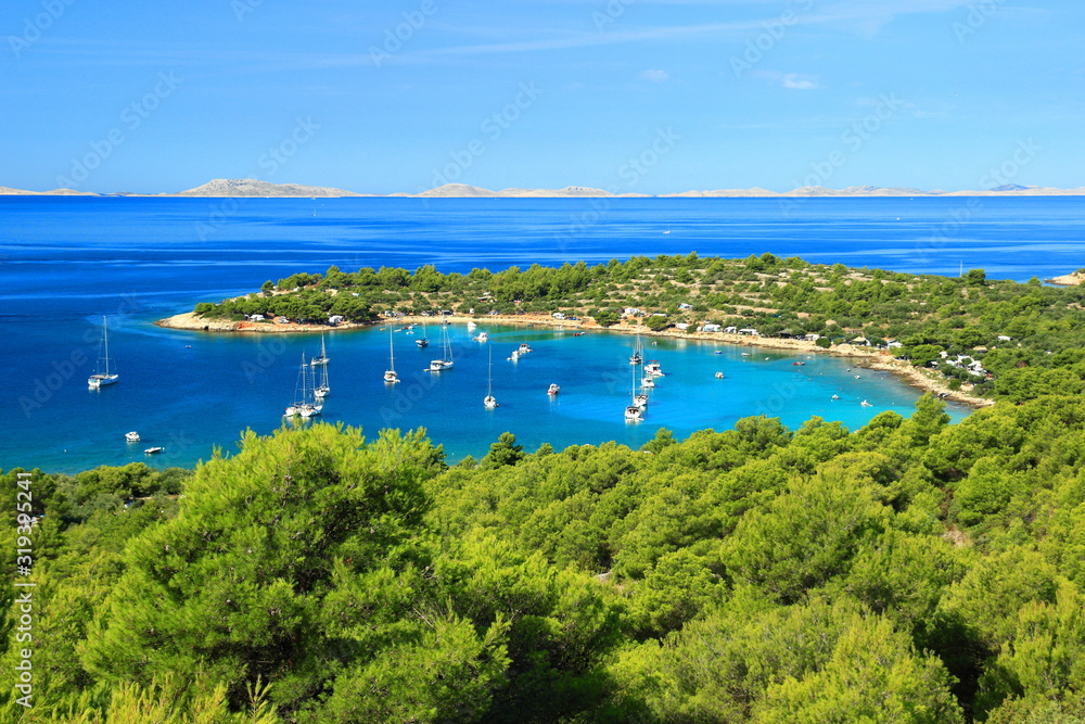 Gorgeous beach Kosirina with clear turquoise sea on island Murter in Croatia. Famous touristic destination, National park Kornati, on horizon.