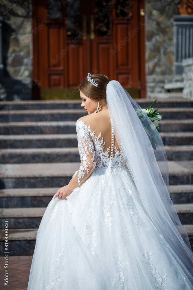 bride in a beautiful white and long dress on a background of a brick building bride in a beautiful white and long dress on a background of a brick building