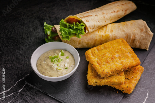 Wallpaper Mural Close up tortilla wrap with salmon and fresh salad, breaded fish fillet and sauce on a black cutting board Torontodigital.ca