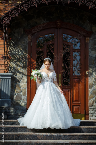 bride in a white dress with a bouquet in her hands and a crown on her head