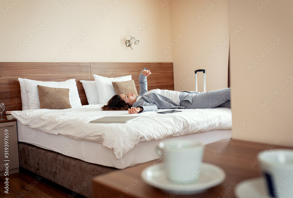 Young businesswoman lying on hotel bed exhausted from the business trip.