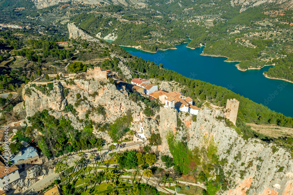 Panoramic view of popular Spanish vacation destination El Castell de Guadalest above a beautiful water reservoir with 2 castles and fortified enclave