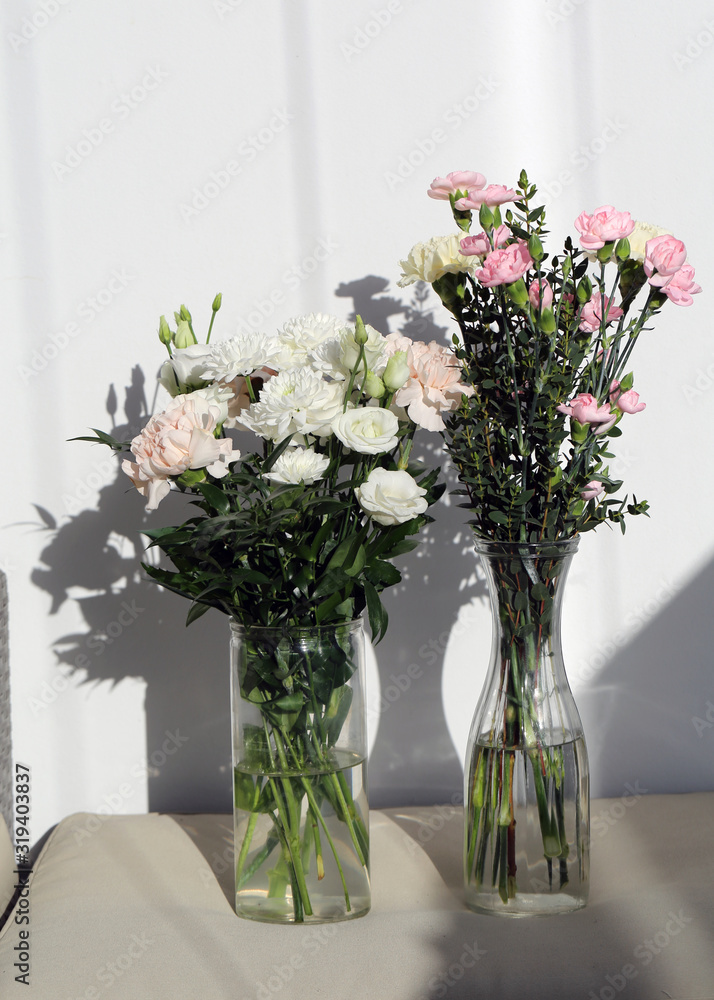 Super cute, light color flower bouquets including baby pink and white dianthus flowers with white chrysanthemum flowers, and some other white flowers. Photographed with a white wall on the background. Super cute, light color flower bouquets including baby pink and white dianthus flowers with white chrysanthemum flowers, and some other white flowers. Photographed with a white wall on the background.