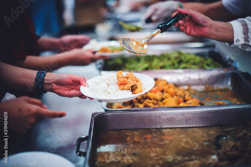 Food donation to hungry people, poor hands waiting to receive free food from volunteers photo