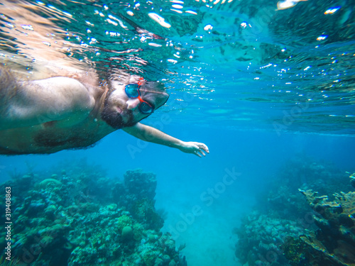 Roatan, Honduras »; December 30, 2019: A tourist with diving goggles bathing at West Bay beach on the Caribbean island Roatan