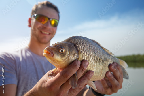 Fototapeta Naklejka Na Ścianę i Meble -  Young happy angler holds the fish
