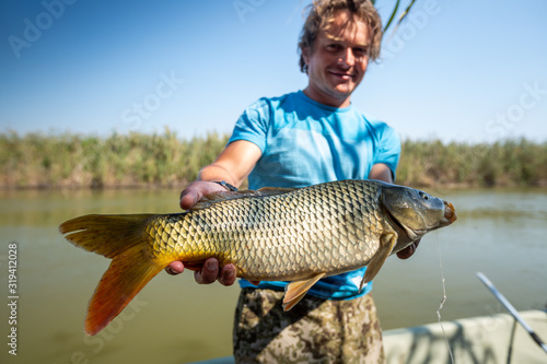 Young happy angler holds the big fish