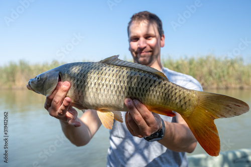 Young happy angler holds the big Carp fish