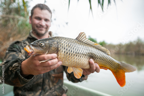 Young happy angler holds the big Carp fish