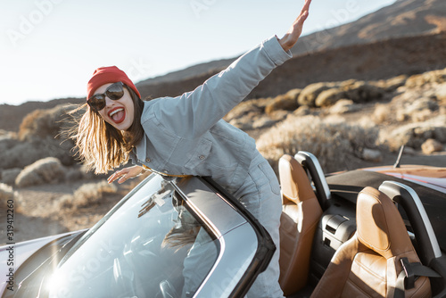 Принти на полотні Lifestyle portrait of a playful woman having fun during a road trip, raising han