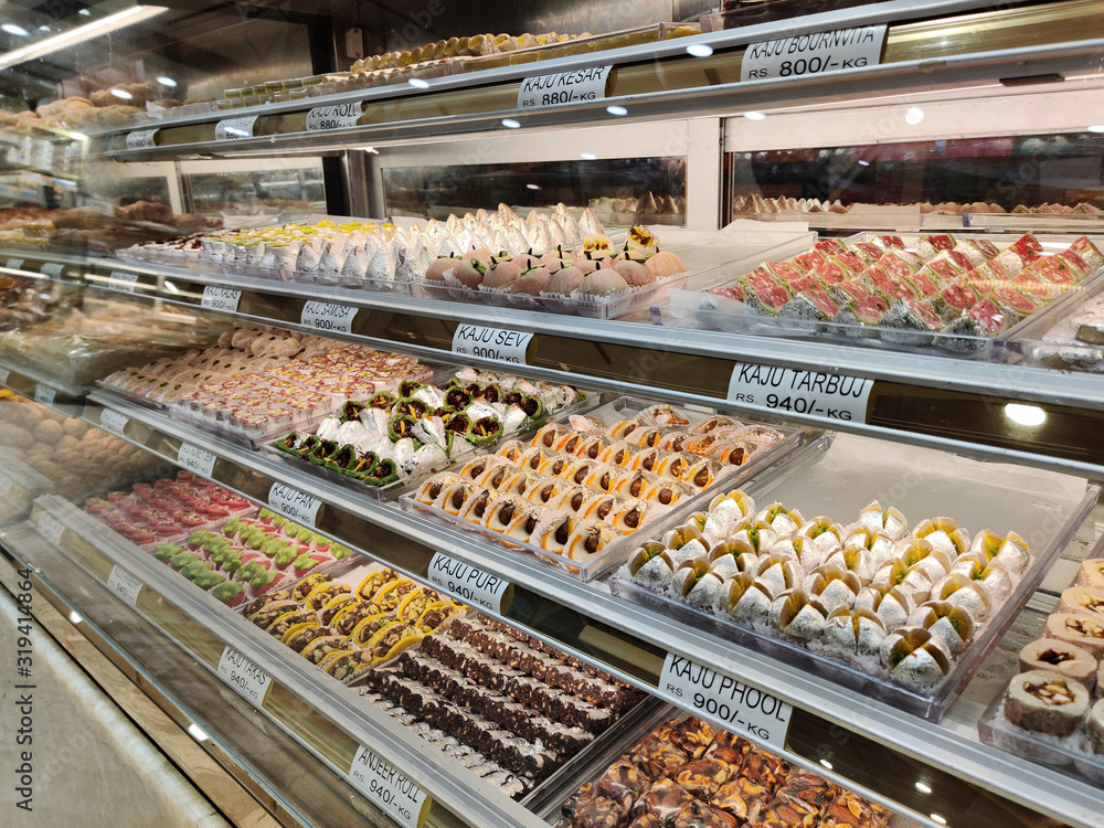 traditional Indian sweets kept in the fridge of a decorated mithai shop. Desserts like Laddoo, Barfi, and other dry fruits like cashew are gifted in festivals and weddings are on display