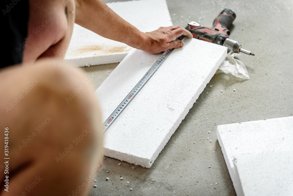 Worker mark the correct length and dimension of styrofoam on construction site.