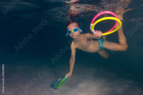Games under water. little boy dives in the pool for colored rings. children's sport.