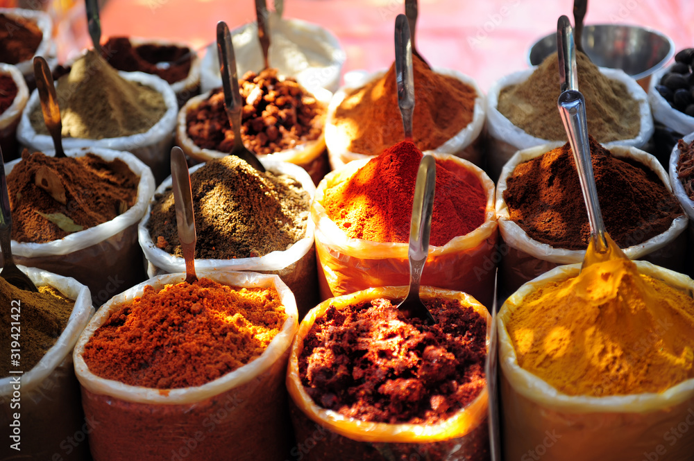 Fototapeta premium Variety of spices on the market in Asia. Powdered spices in bags, close-up. Turmeric, chili pepper, coriander, nutmeg, spices in eastern bazaar.