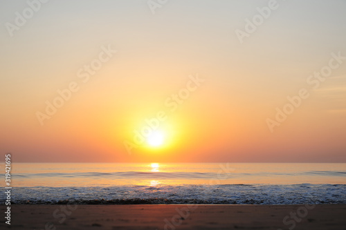 Stunning view of the sea in the rays of setting sun, reddish sunlight reflected in the water. Beautiful sunset over the ocean, deserted beach, copy space. © exebiche