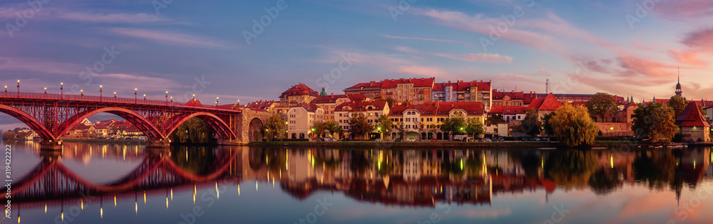 Amazing view of Maribor Old city, Main bridge (Stari most) on the Drava river before sunrise, Slovenia. Scenic cityscape with color sky and reflection, travel background for wallpaper, large panorama