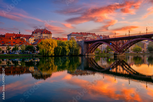 Amazing view of Maribor Old city, Main bridge (Stari most) on the Drava river before sunrise, Slovenia. Scenic cityscape with color sky and reflection, travel background for wallpaper or guide book photo