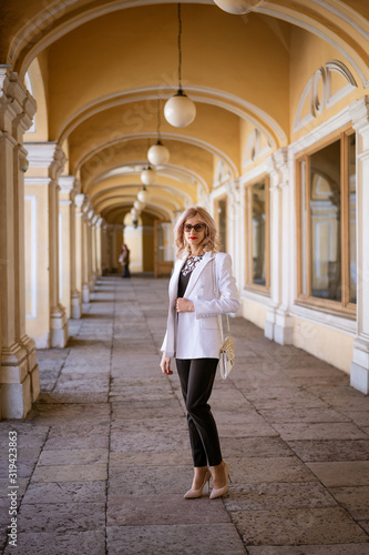 a business woman in a white jacket stands on the street