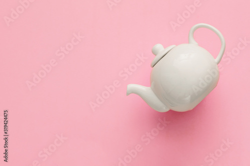 White porcelain teapot on a pink background, minimal art, close-up, flat lay