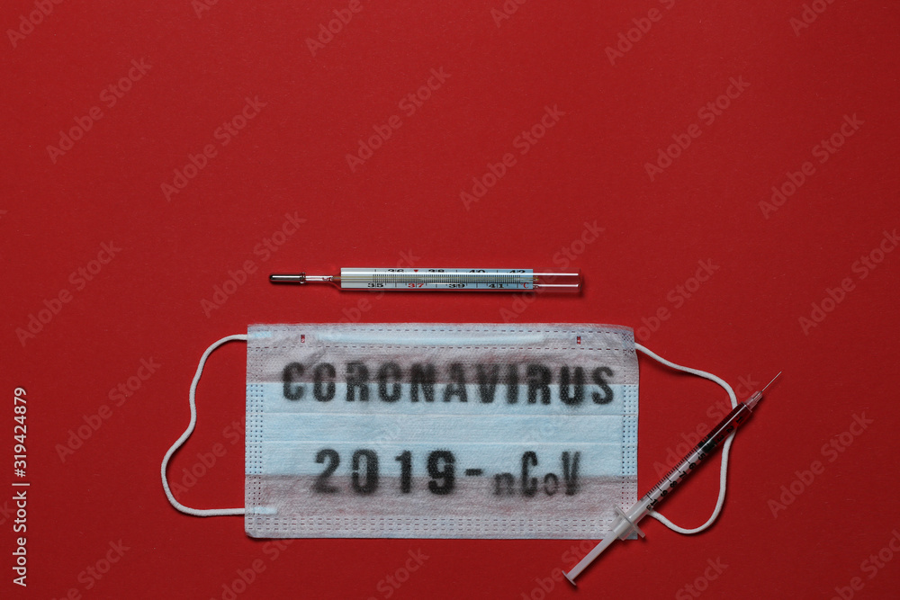 The medical respiratory bandage on the face. Pills, syringe and thermometer. Pandemic virus infection from Wuhan, China. Red background The medical respiratory bandage on the face. Pills, syringe and thermometer. Pandemic virus infection from Wuhan, China. Red background