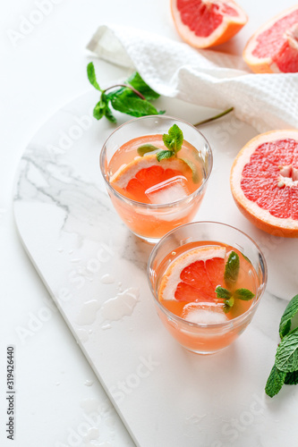 Healthy grapefruit drink with mint on a white marble tray