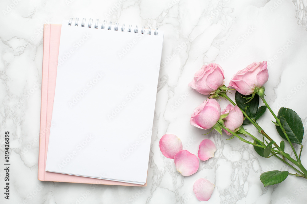 Beautiful pink roses flower and notebook on marble background.Minimalistic composition for the holidays,valentines day and womens day. Beautiful pink roses flower and notebook on marble background.Minimalistic composition for the holidays,valentines day and womens day.
