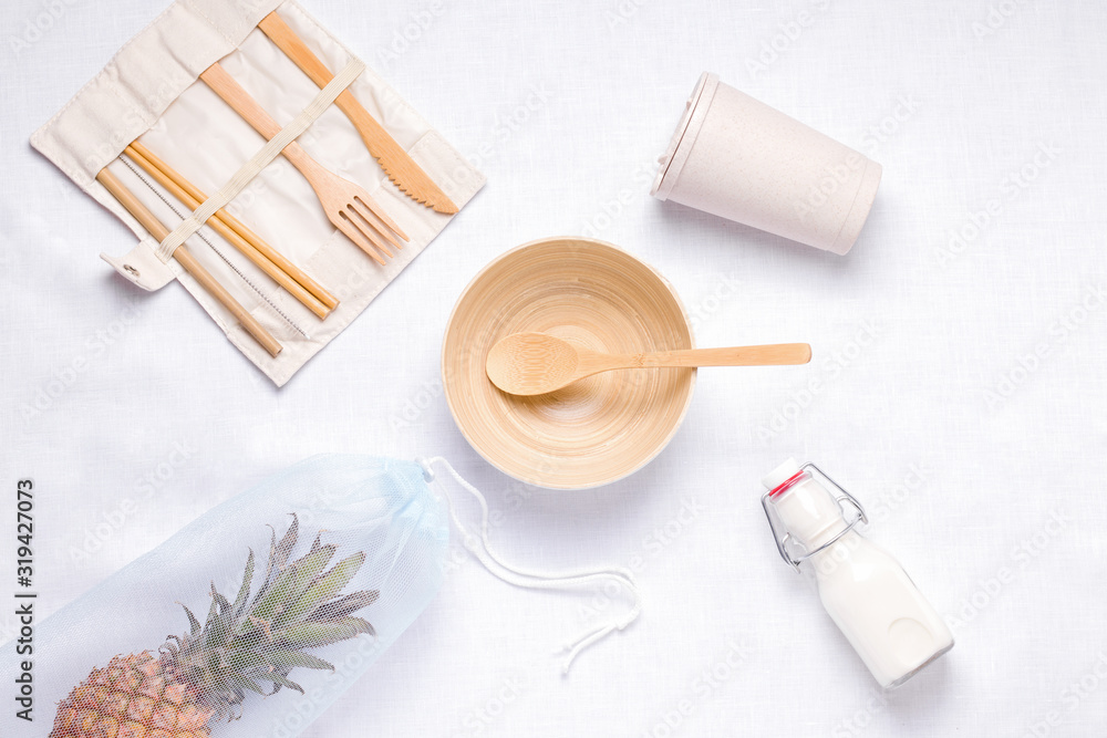 on a white table are kitchen utensils made of wood and a shopping bag with pineapple.Zero Waste on a white table are kitchen utensils made of wood and a shopping bag with pineapple.Zero Waste