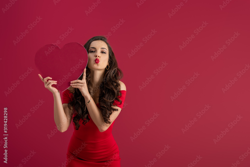 sexy, elegant girl holding paper heart while sending air kiss at camera isolated on red sexy, elegant girl holding paper heart while sending air kiss at camera isolated on red