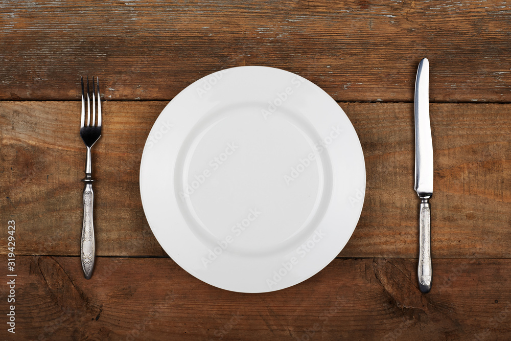 Empty plate with fork and knife on the vintage wooden table Empty plate with fork and knife on the vintage wooden table