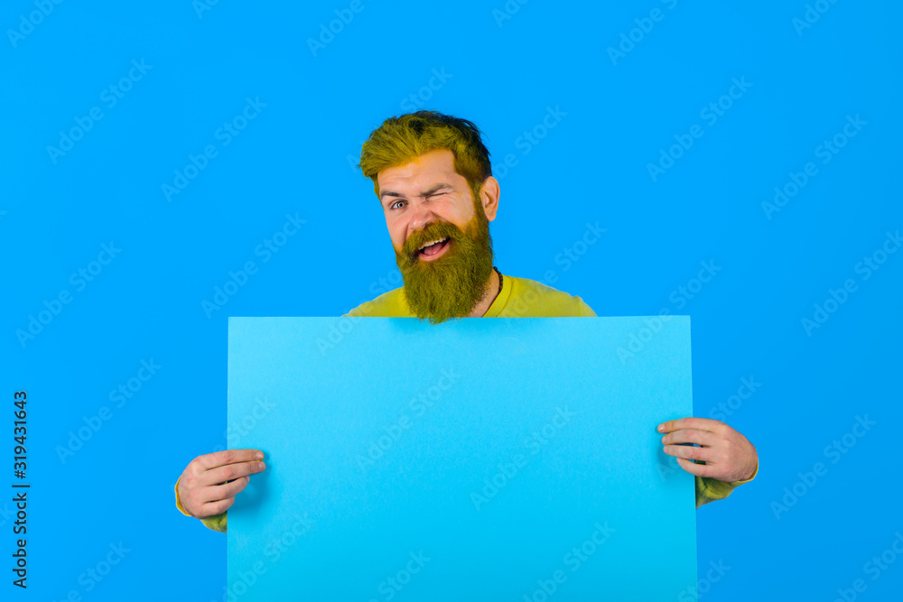Winking bearded man holds advertising board. Seasons sale. Discount. Black friday. Advertising and sale. Online shopping. Advertising banner. Barber fashion and beauty marketing. Copy space for text. Winking bearded man holds advertising board. Seasons sale. Discount. Black friday. Advertising and sale. Online shopping. Advertising banner. Barber fashion and beauty marketing. Copy space for text.